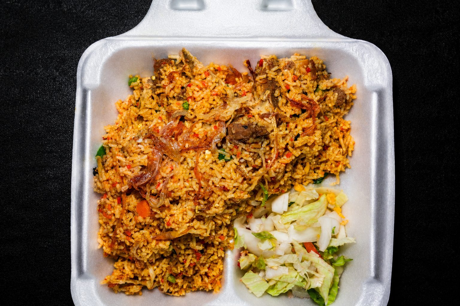 Layered biryani with saffron rice and tender meat — food photography